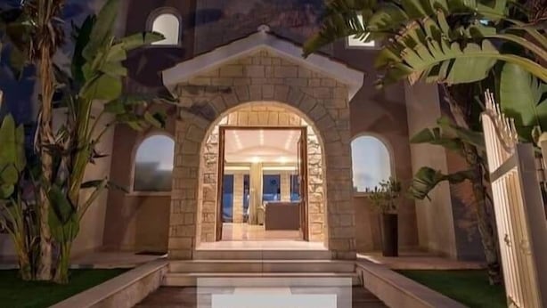 A building with a stone entrance, a central archway, and a paved pathway leading to the entrance. - villa kristia (Paphos)