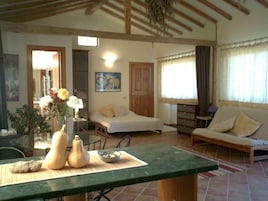 Una habitación acogedora con una cama, un sofá, una mesa de comedor con un cuenco y dos calabazas, y un cuadro en la pared.