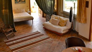 A spacious room with a bed, a sofa, and a dining area with a table set for two.