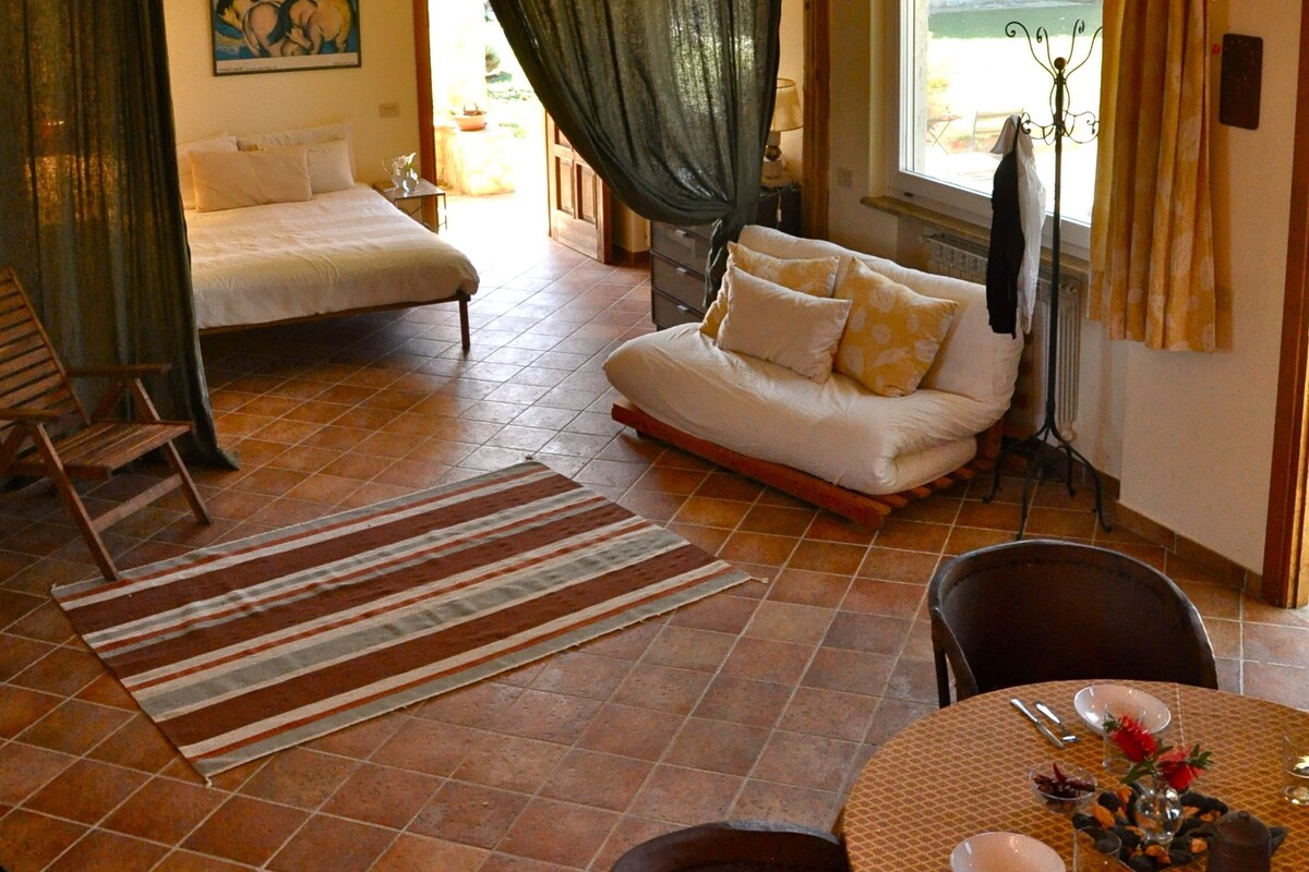 Amplia habitación con cama, sofá y zona de comedor con mesa dispuesta para dos.