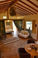 A spacious room with a bed, a sofa, and a dining area with a table set for two.