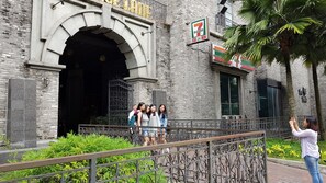 A historic building with a large arched entrance, a 7-Eleven convenience store, and a gated area with a metal fence. - Duplex Loft Empire Damansara (Petaling Jaya)