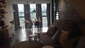 A living room with a sofa, a coffee table, and a dining area with chairs and a table. - Duplex Loft Empire Damansara (Petaling Jaya)