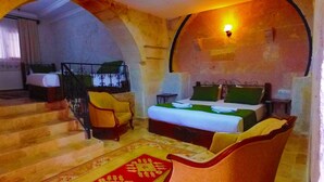 A hotel room with a bed, two chairs, a small table, and a staircase. - Kufe Hotel (Nevsehir)