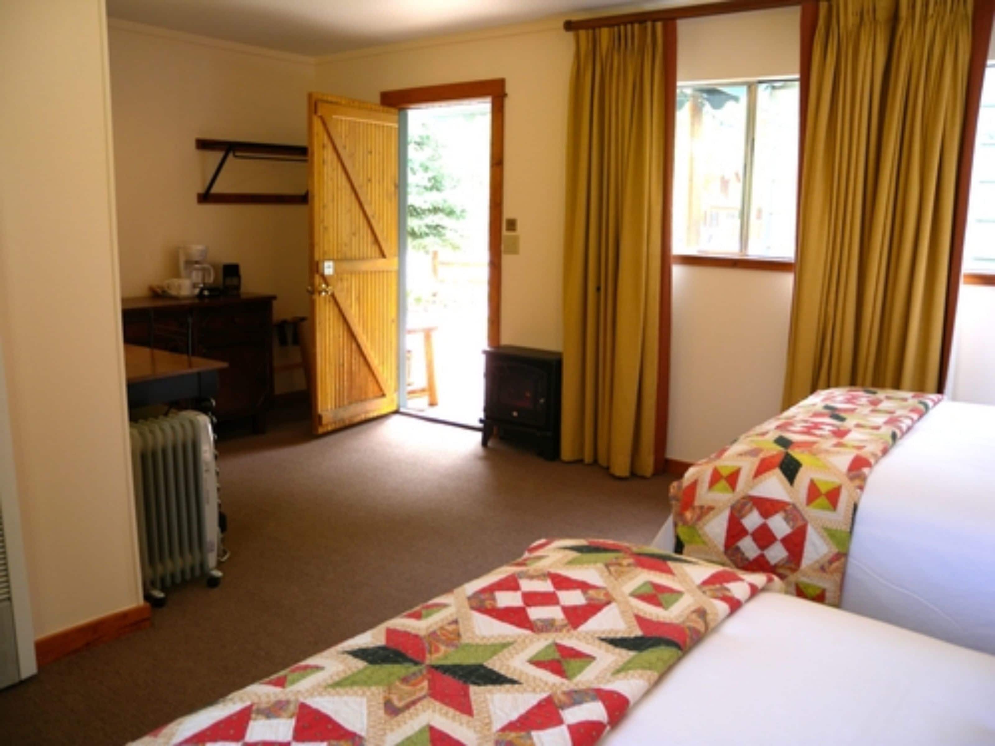 Een hotelkamer met een bed, een bureau, een radiator en een deur naar buiten.