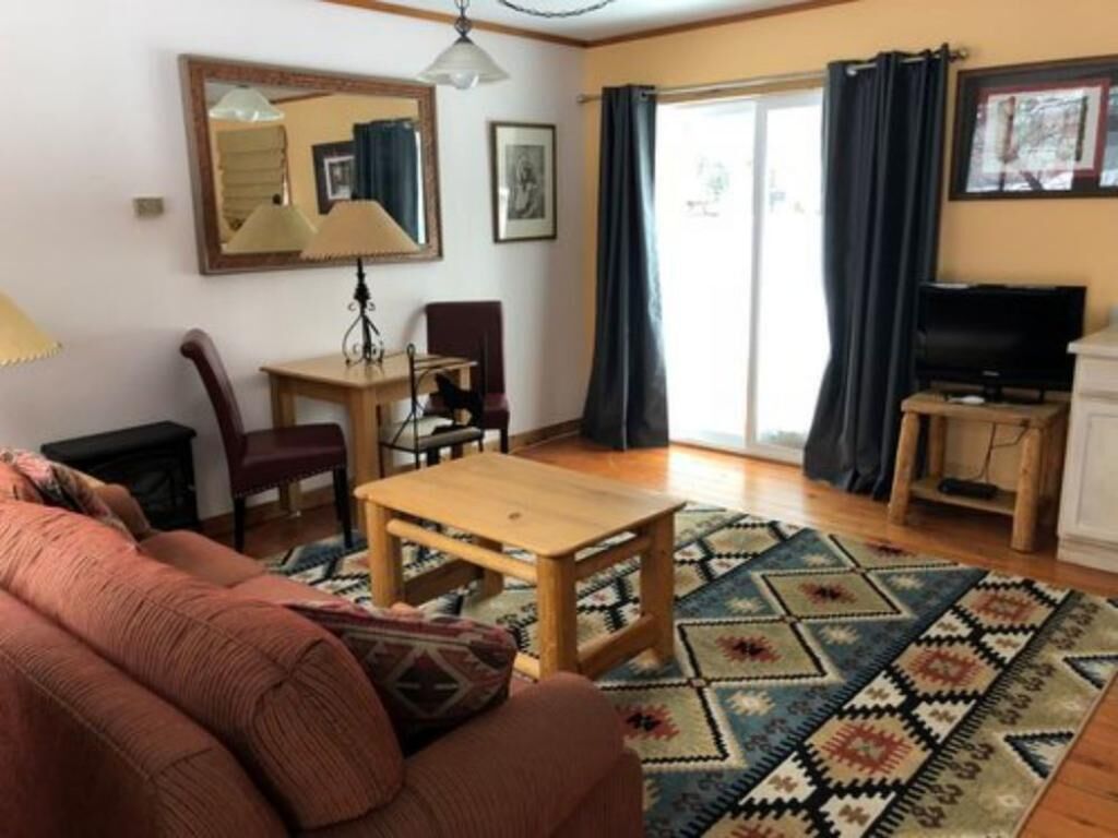 Una sala de estar con un sofá, una mesa de centro de madera, un televisor y un comedor con sillas y una mesa.