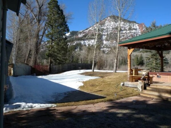 Un espacio al aire libre techado con una terraza de madera y un paisaje montañoso al fondo.