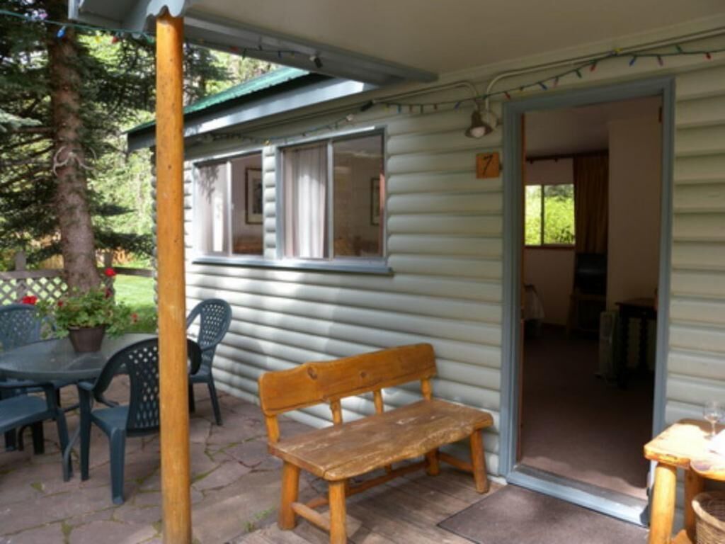 A wooden bench outside a house with a covered patio area.