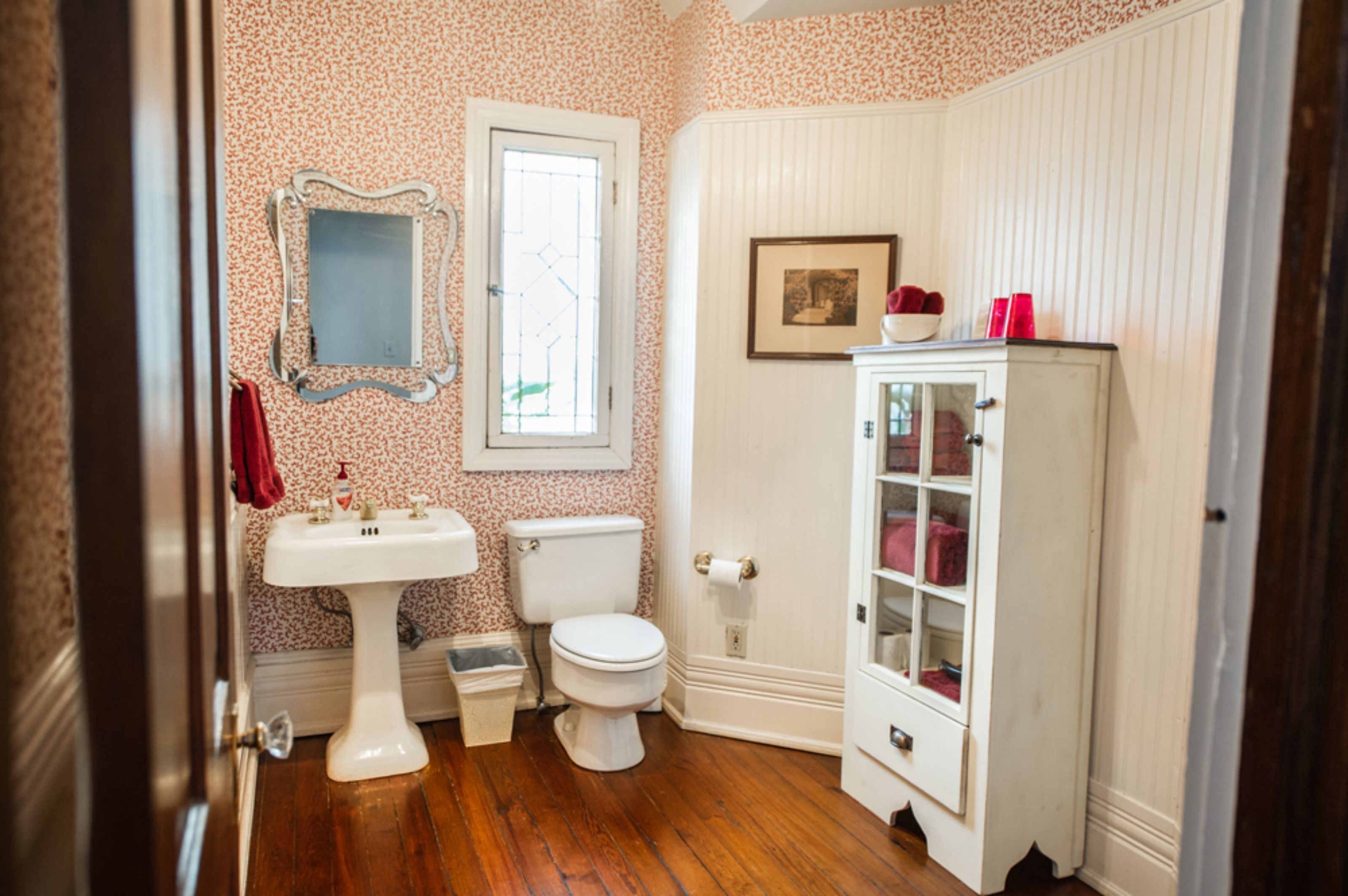 Casa de banho com lavatório branco, sanita e armário com portas de vidro.