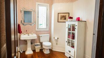 Casa de banho com lavatório branco, sanita e armário com portas de vidro.