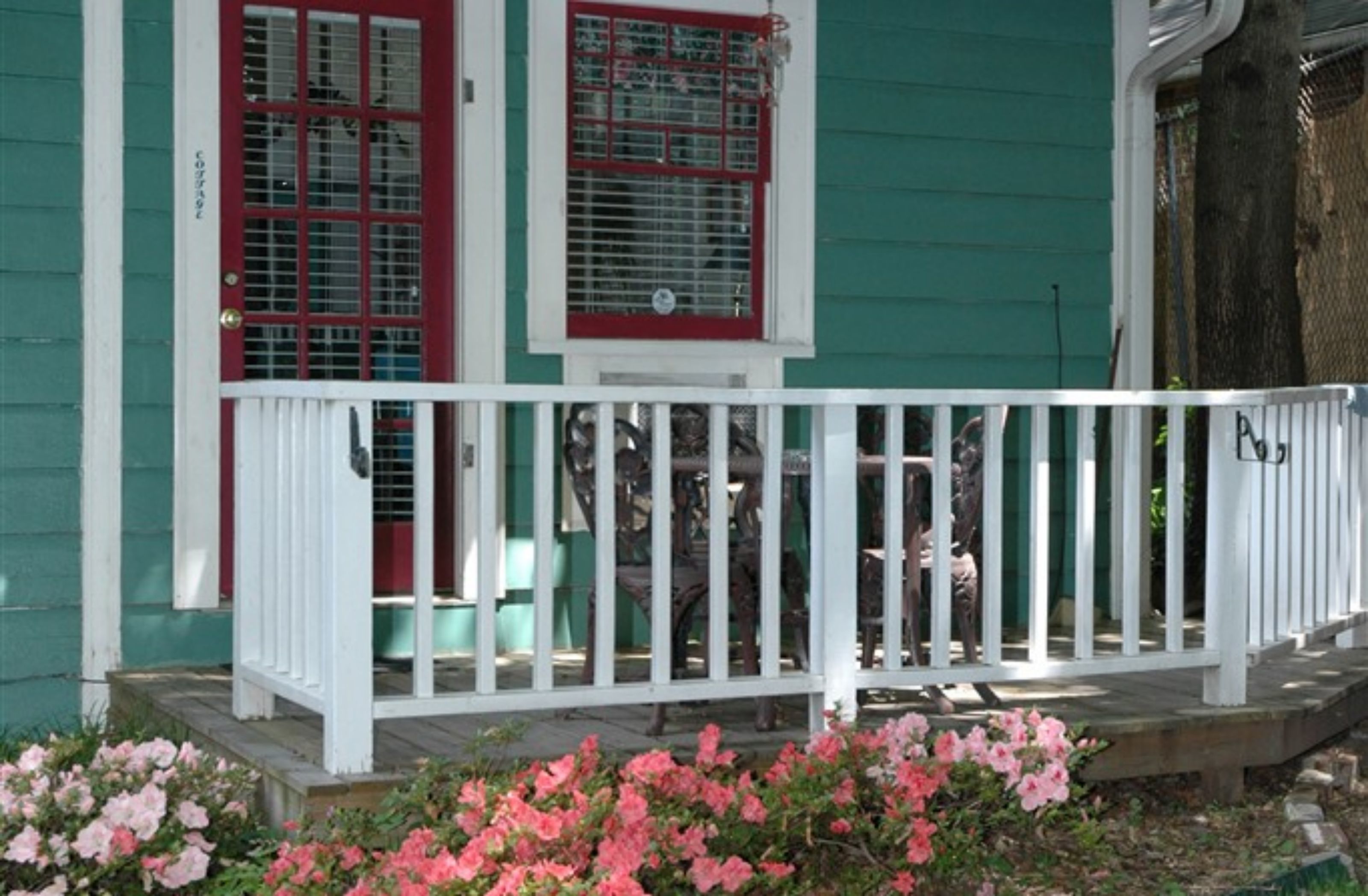 A house with a white porch and red-framed windows.
