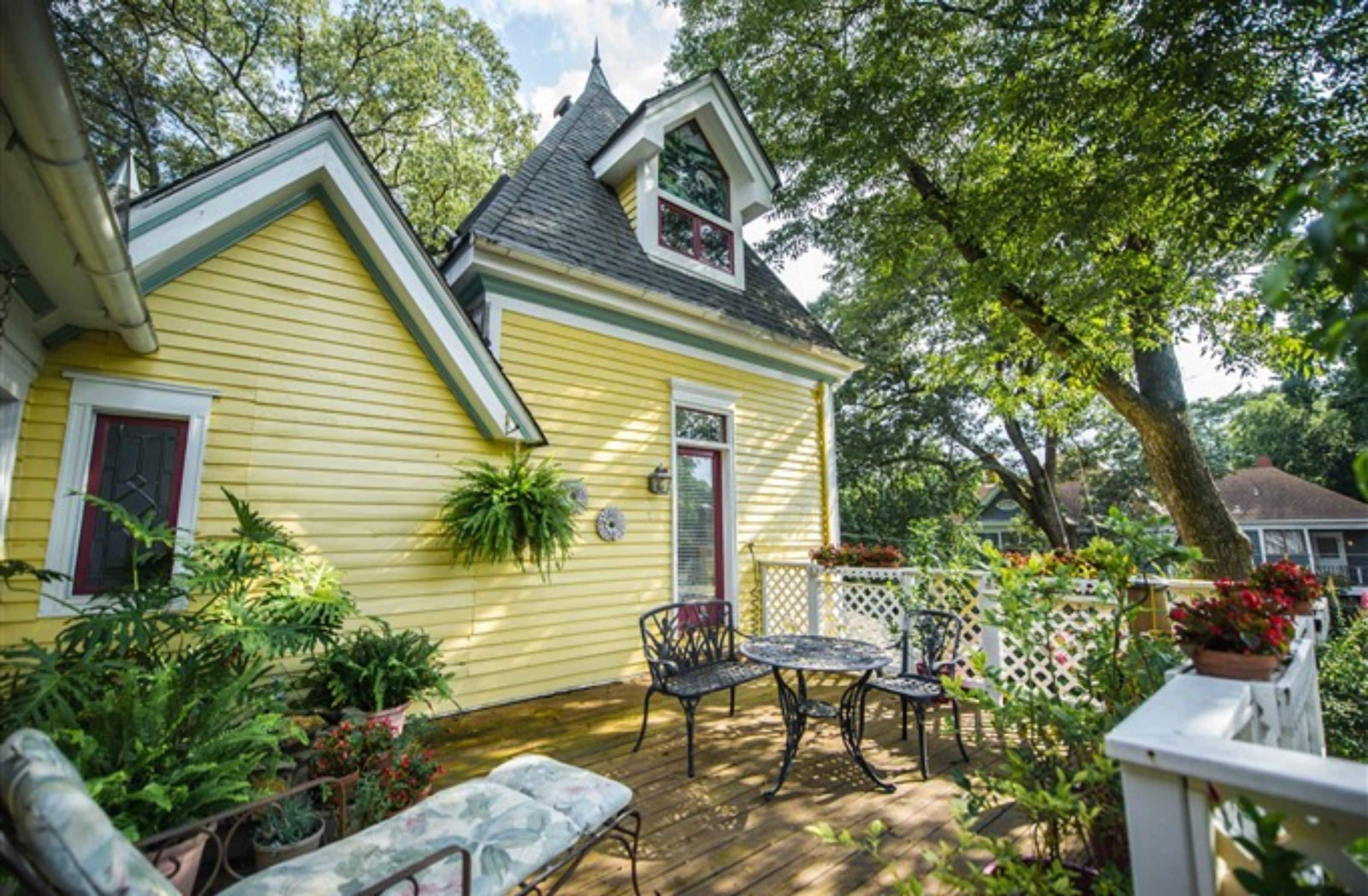 A yellow house with a covered porch, a small garden, and outdoor furniture.