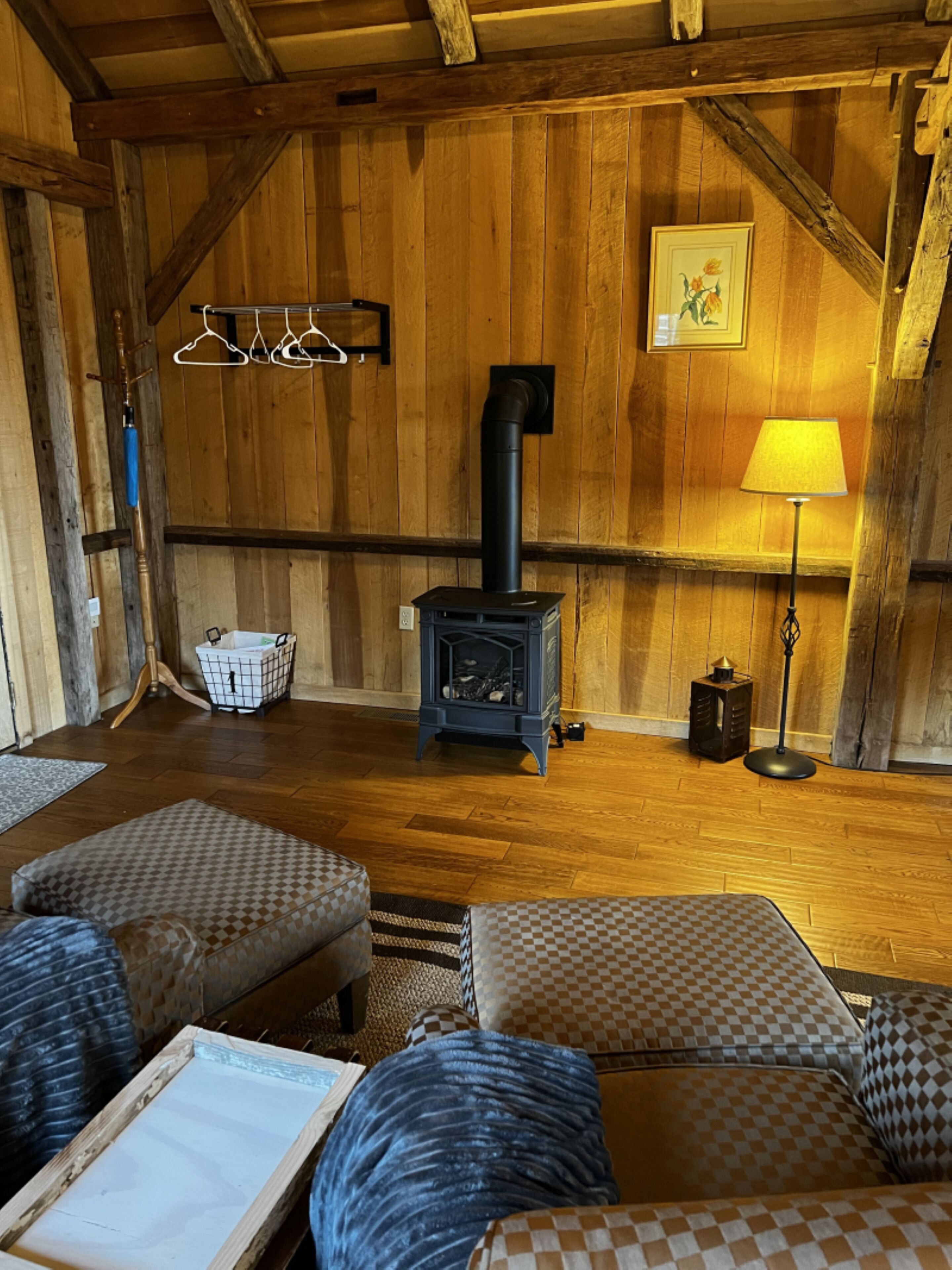 A cozy room with wooden walls, a fireplace, a sofa, and a lamp.