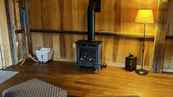 A cozy room with wooden walls, a fireplace, a sofa, and a lamp.