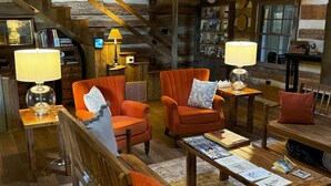 A rustic cabin interior with wooden furniture, a staircase, and a cozy fireplace.