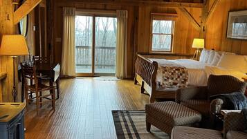 A cozy cabin interior with a wooden floor, a bed, a sofa, and a dining area with a table and chairs.