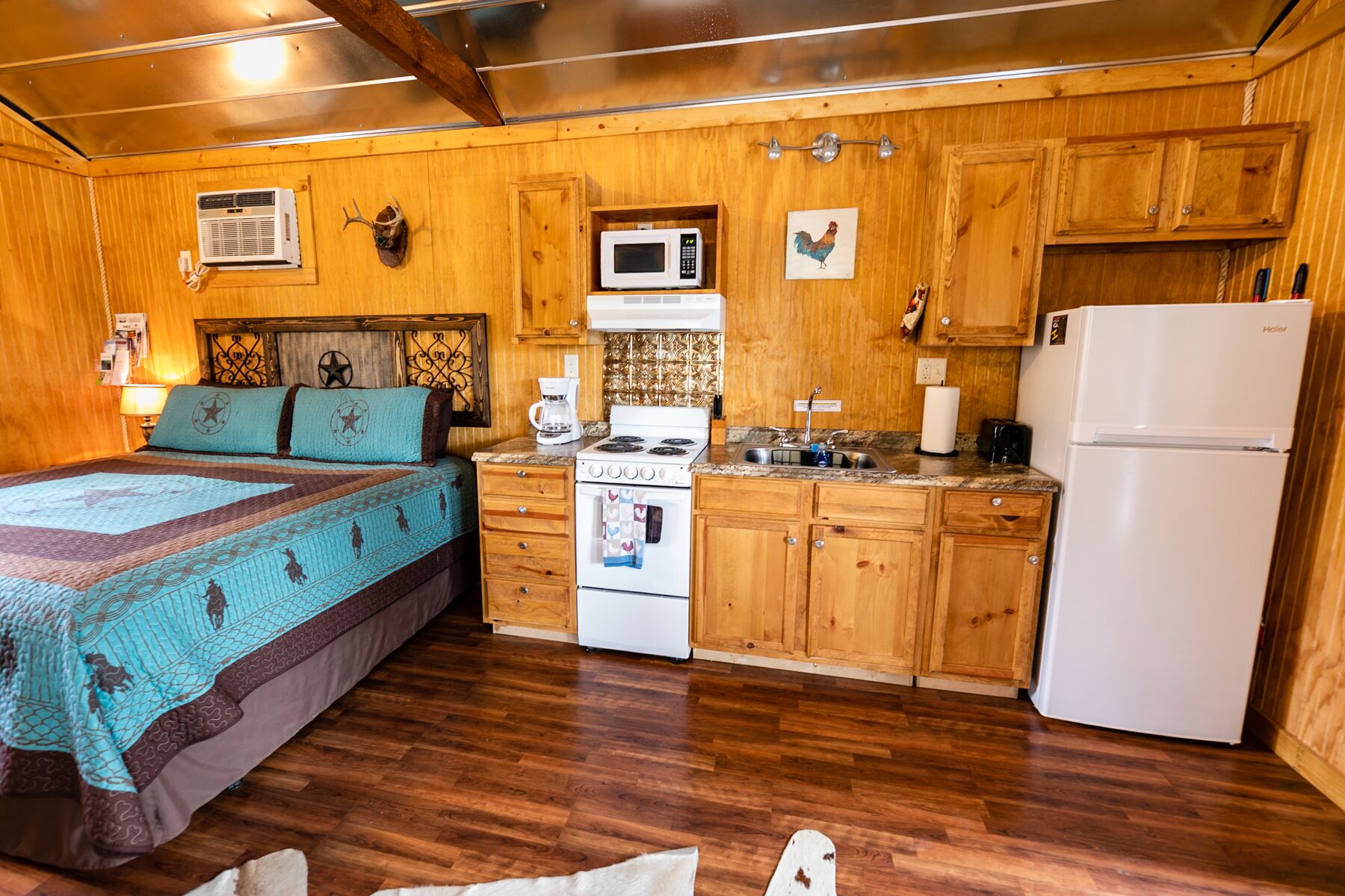Una habitación acogedora estilo cabaña, con cama, armarios de madera, estufa y refrigerador.