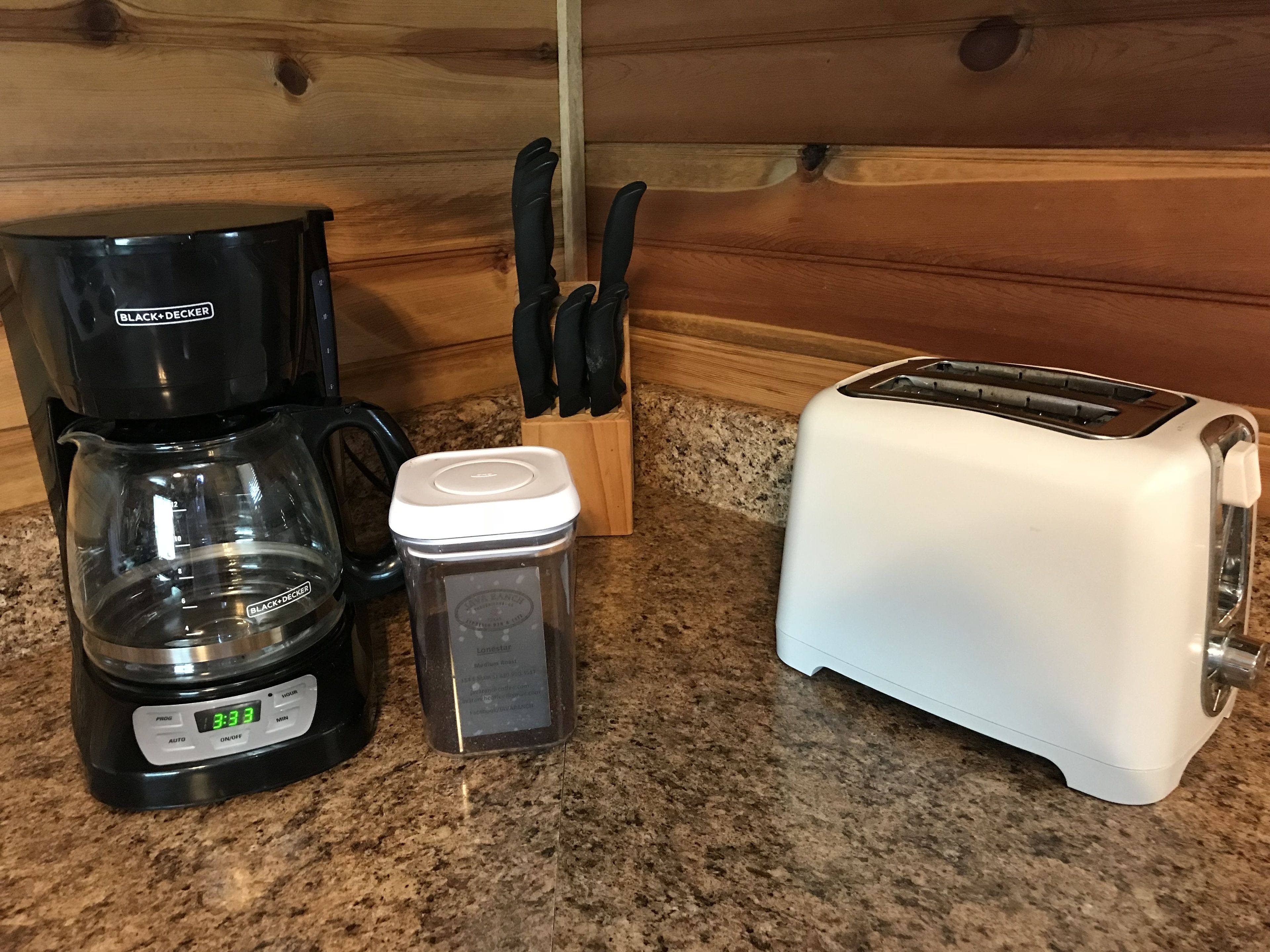 En köksbänk med en kaffebryggare, en behållare och en brödrost.