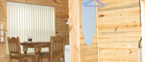 Un interior de madera con una mesa de comedor y sillas, un televisor montado en la pared y un perchero colgado.