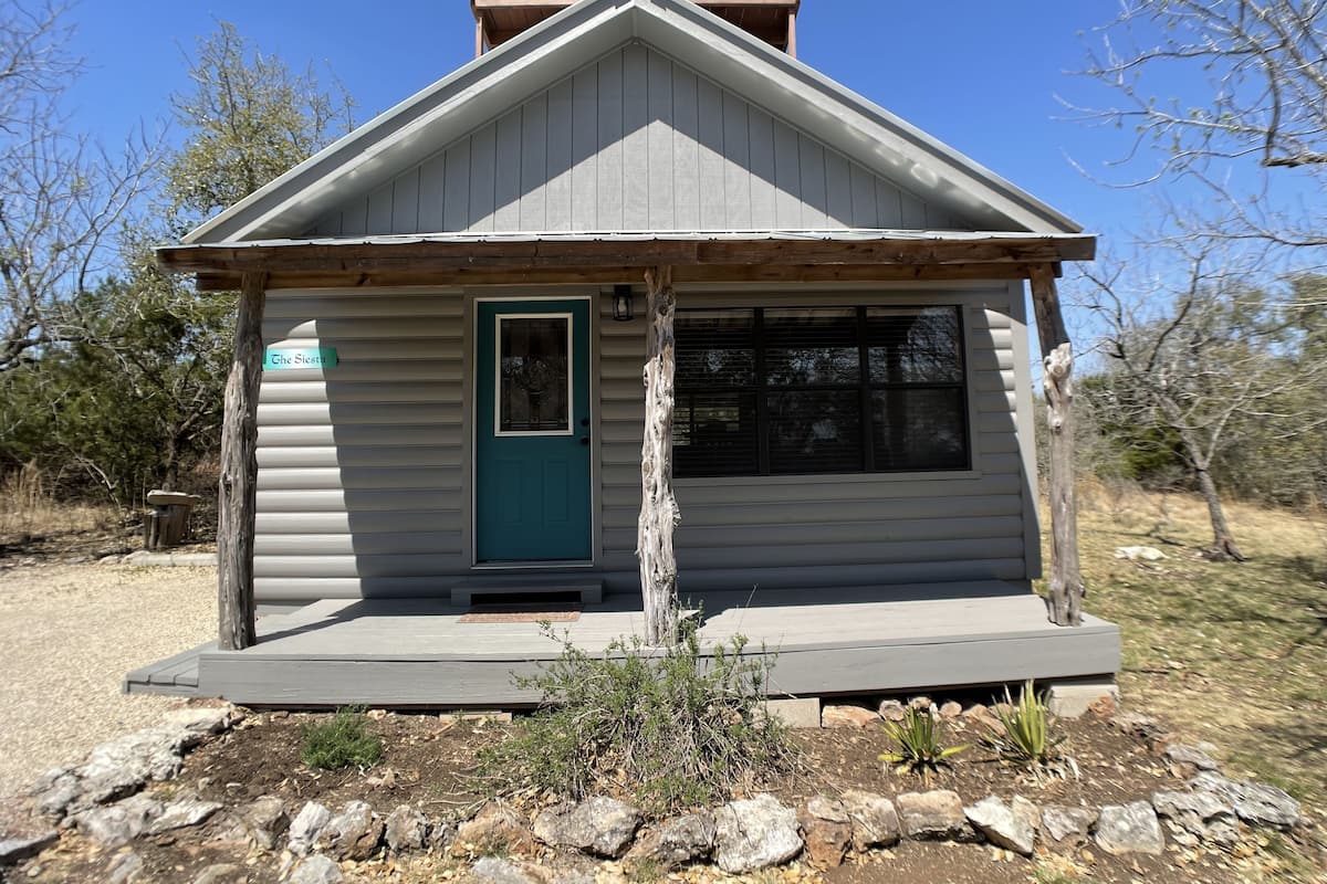 A small cabin with a green door, a window, and a wooden porch.
