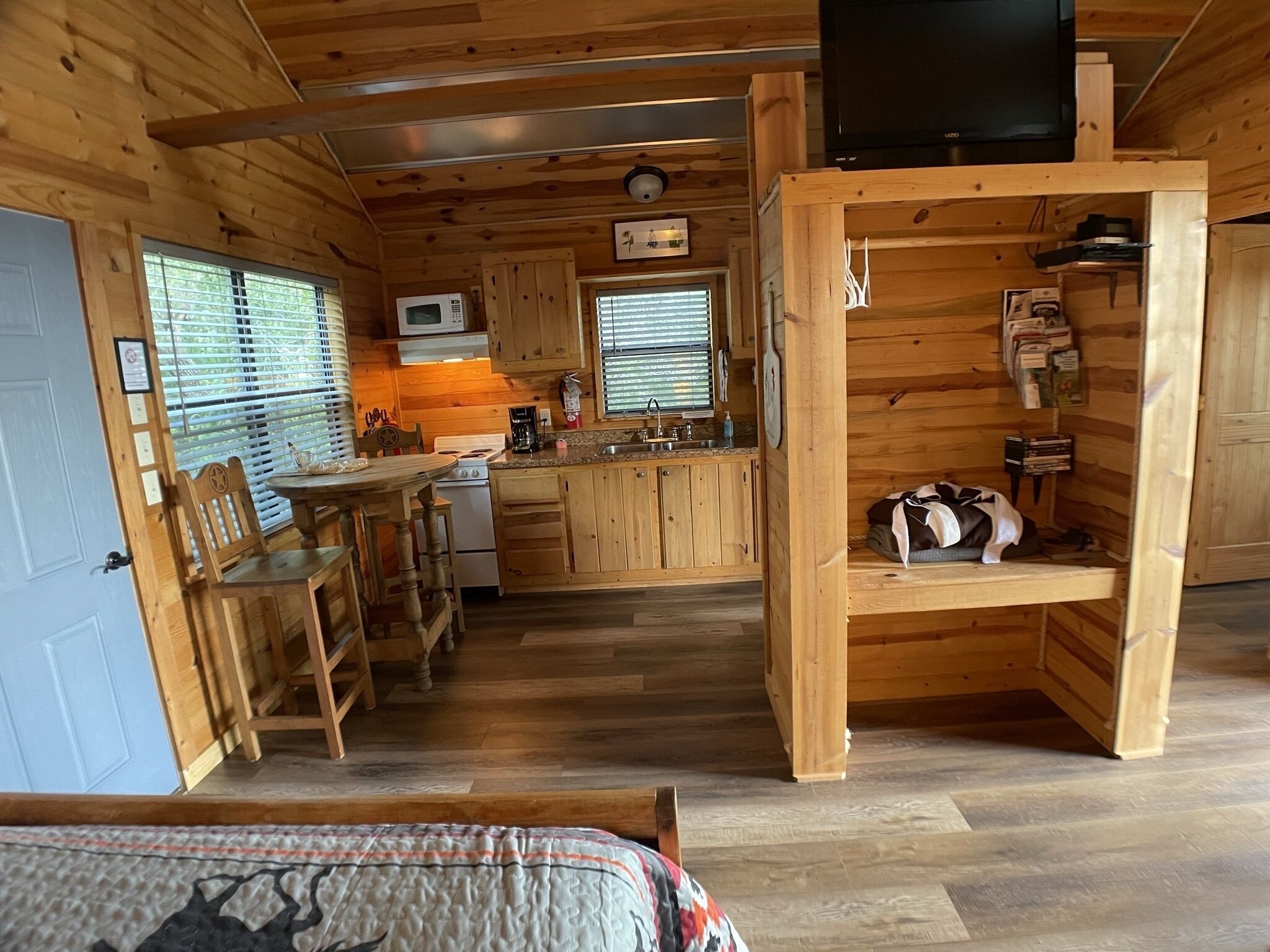 Accogliente camera in stile chalet con pareti in legno, angolo cottura, zona pranzo e TV a parete.