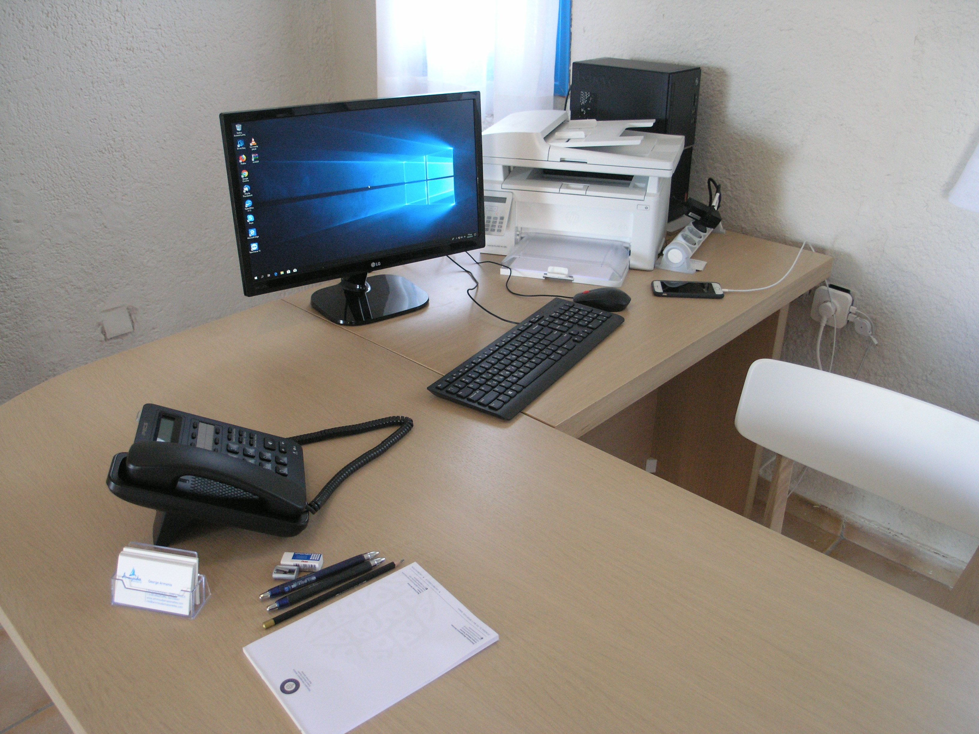 Un escritorio con monitor de computadora, teclado, ratón y teléfono.
