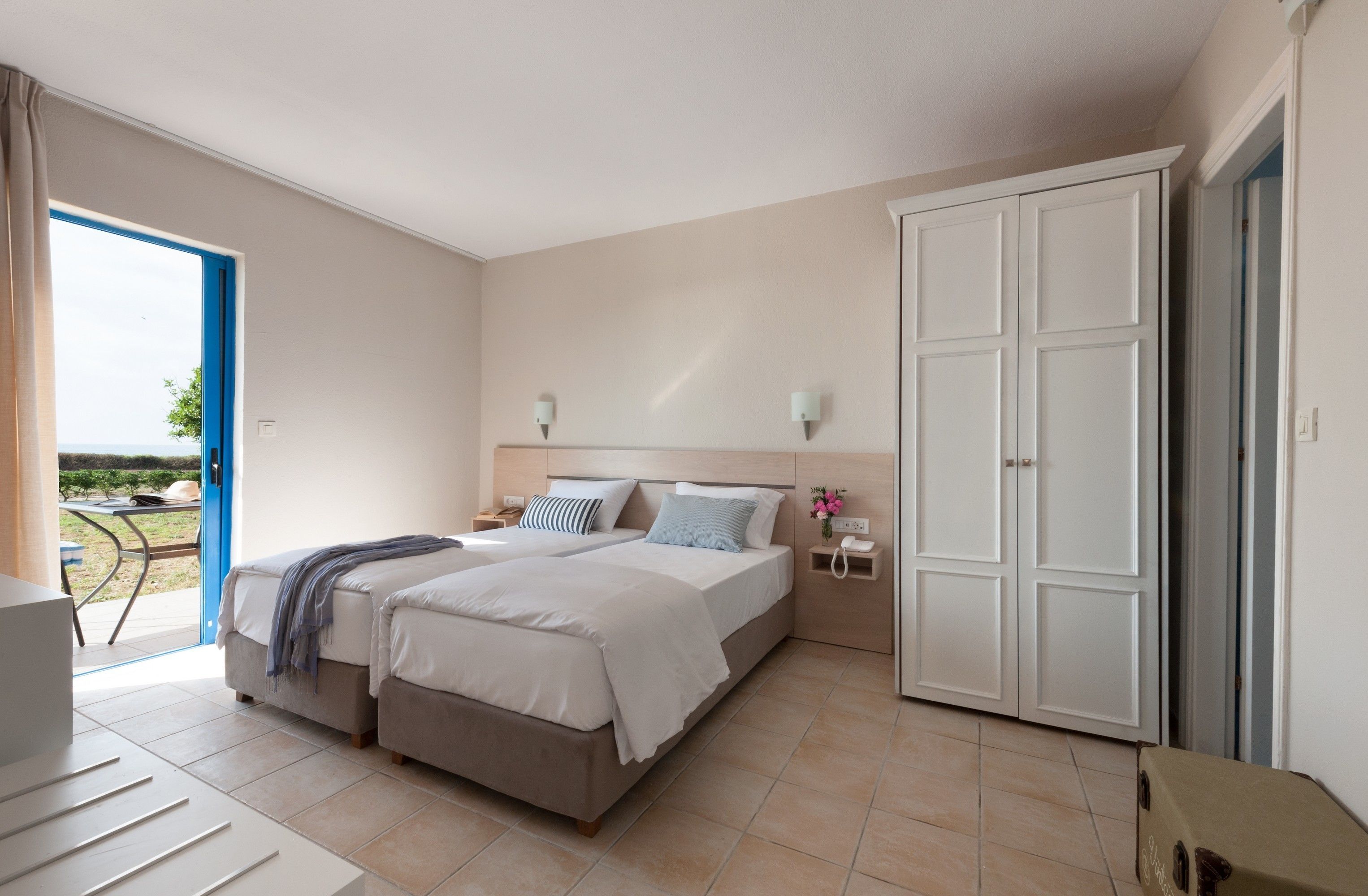 A bedroom with a bed, bedside tables, a wardrobe, and a view of the outdoors.