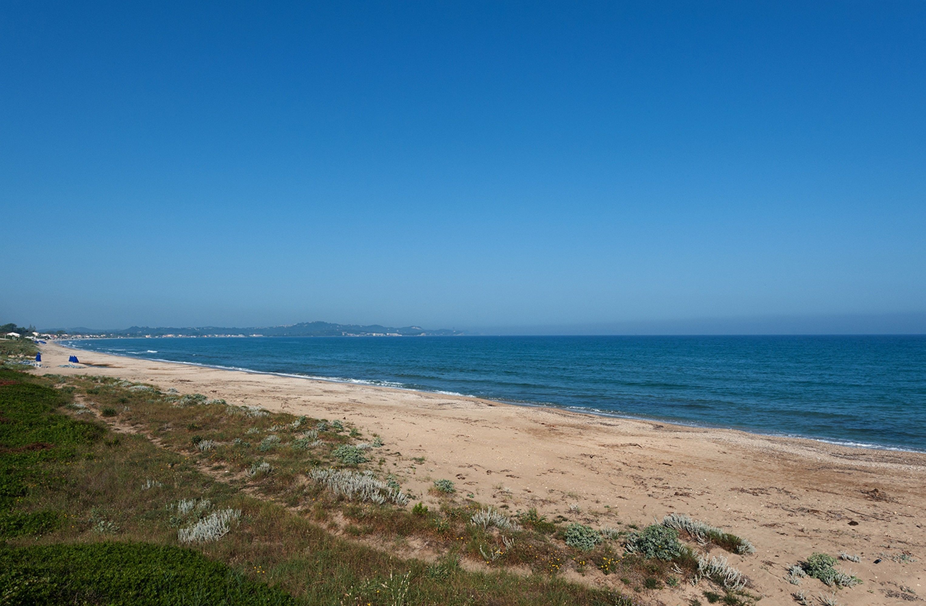 Ein Strand mit blauem Himmel und ruhigem Wasser.