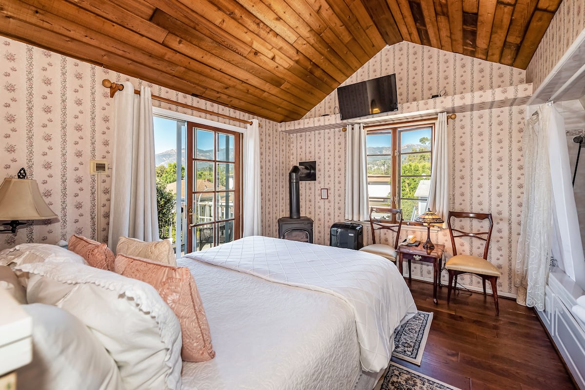 Um quarto acolhedor com uma cama grande, teto de madeira e lareira.