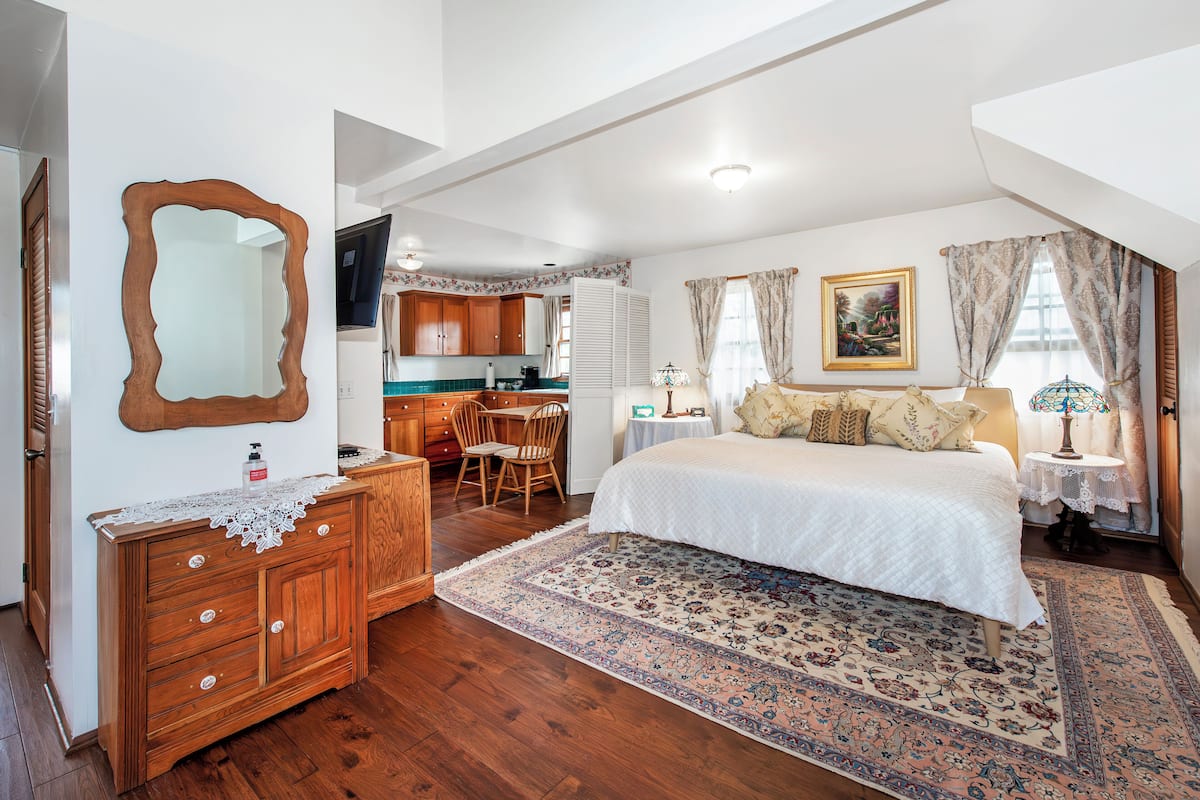 Quarto com uma cama grande, cômoda de madeira e televisão no canto.