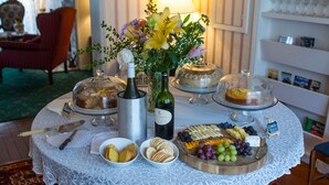 A table with a variety of food items, a bottle of wine, and a floral centerpiece. - Bath Street Inn (Santa Barbara)