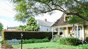 A house with a porch, a sign for '1720 the Bath Street Inn Bed & Breakfast', and a flag. - Bath Street Inn (Santa Barbara)