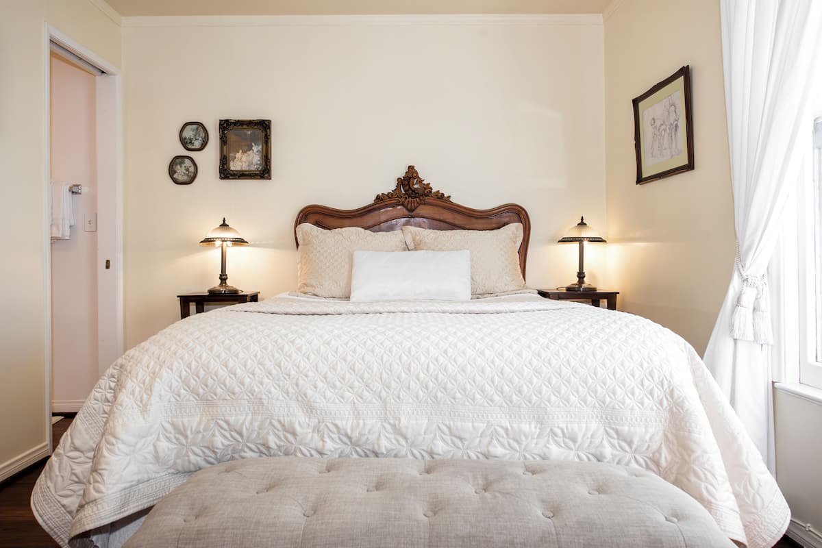 Uma cama bem arrumada com cobertura acolchoada, duas luminárias de cabeceira e um quadro na parede.