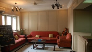A hotel lobby with a red sofa, a small table, and a statue. There is a sign on the left and a window with a 'No Smoking' sign. - Park Palace Hotel (Kolkata)