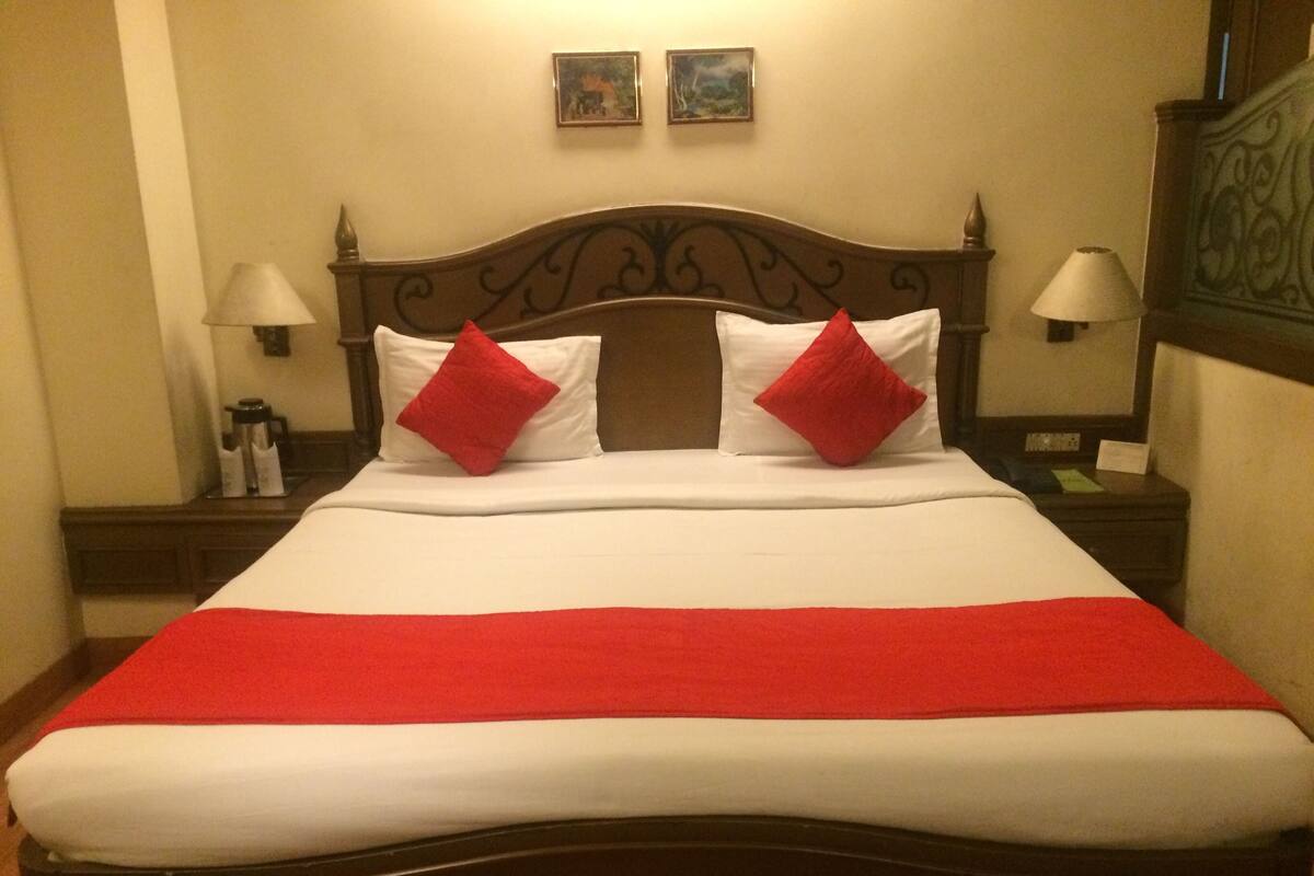 Una cama bien hecha con ropa de cama blanca y roja, dos almohadas rojas y una manta roja.