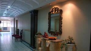 A hallway with a marble bench, a decorative mirror, and potted plants. - Park Palace Hotel (Kolkata)
