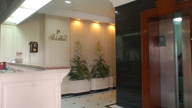 A hotel reception area with a marble counter, a clock, and two potted plants. - Park Palace Hotel (Kolkata)
