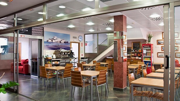 A modern cafeteria with tables and chairs, a staircase, and a vending machine. - Hotel Marina Peñíscola (Peniscola)