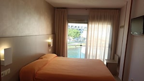 A hotel room with a bed, a bedside telephone, and a TV on the wall. - Hotel Marina Peñíscola (Peniscola)