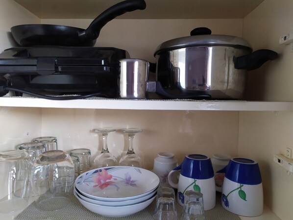 A kitchen shelf with cookware and glassware. - Kaluva Studios (Kos)