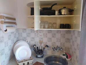A compact kitchen with a sink, dish rack, and a utensil holder.