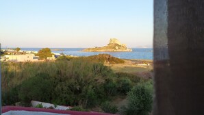 Vista costera con una isla rocosa y edificios a lo lejos.