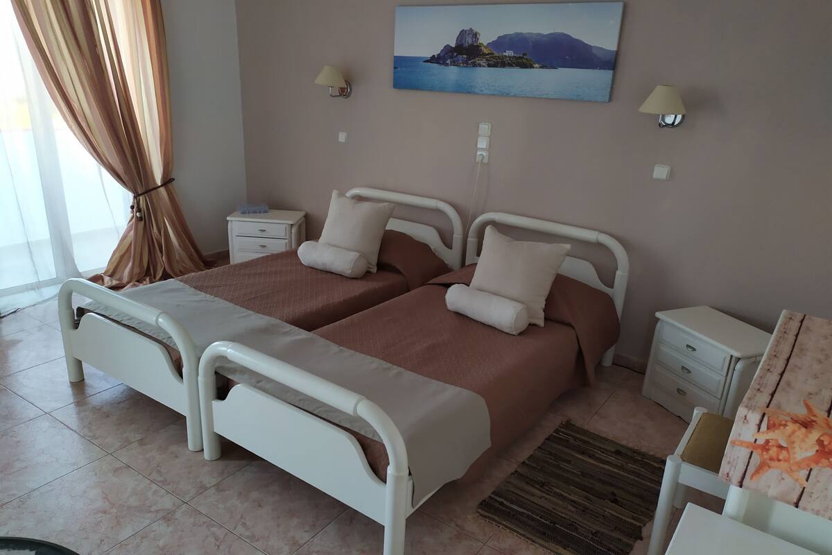 A double bed with a headboard, a bedside table, a nightstand, a lamp, and a painting on the wall.