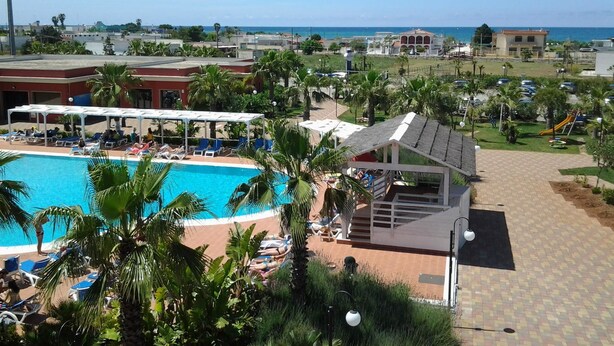 A resort with a swimming pool, lounge areas, and a view of the ocean. - Baiamalva Resort (Porto Cesareo)