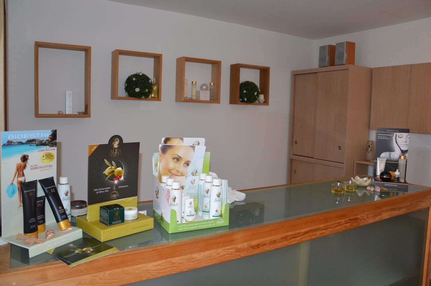 Un área de recepción con un mostrador de vidrio, armarios de madera y varios productos para el cuidado de la piel exhibidos en estantes y sobre el mostrador.
