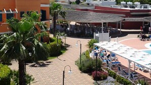 A rooftop pool area with lounge chairs and umbrellas, surrounded by palm trees and a covered seating area. - Baiamalva Resort (Porto Cesareo)
