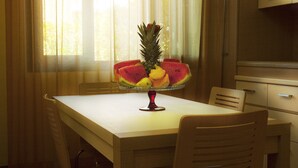A dining table with a fruit centerpiece, wooden chairs, and a window with curtains. - Baiamalva Resort (Porto Cesareo)