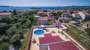 Un quartier résidentiel doté d’une piscine, de toits recouverts de tuiles rouges et offrant une vue sur la mer.