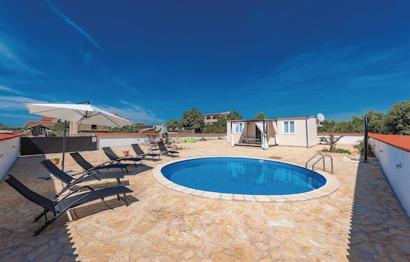 A rooftop swimming pool with lounge chairs and a small building with a white exterior. - Cozy home in Pakostane (Pakostane)