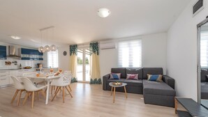 Un appartement moderne comprenant un coin repas, un canapé gris et une cuisine.